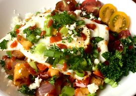 Sweet potato hash served with a fried egg garnished with tomatoes, parsley, and green onions.