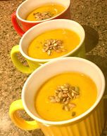 3 bowls of butternut squash soup served with pipits on top.