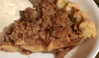 Apple crumb pie served in a bowl with a scoop of vanilla ice cream.