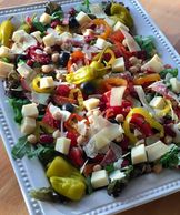 Antipasto salad with pepperoncinis, olives, tomatoes, banana peppers, cheese, salami, peppers.