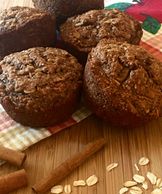 Cinnamon apple oat bran muffins on top of an apple tea towel on a cutting board.