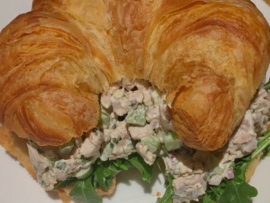 Chicken salad served on a croissant with arugula. 
