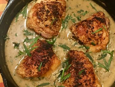 Creamy Tarragon chicken thighs served in a cast iron skillet with fresh tarragon garnish.