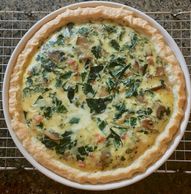 Swiss Chard and pancetta quiche served in a pie pan on top of a cooling rack.