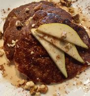Pear Pancakes topped with fresh pear slices, walnuts, cinnamon, and syrup.