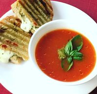Tomato soup with grilled cheese topped with fresh pesto and basil.