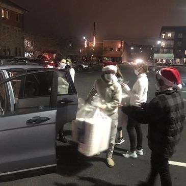 People in masks and Santa hats unloading items at night.