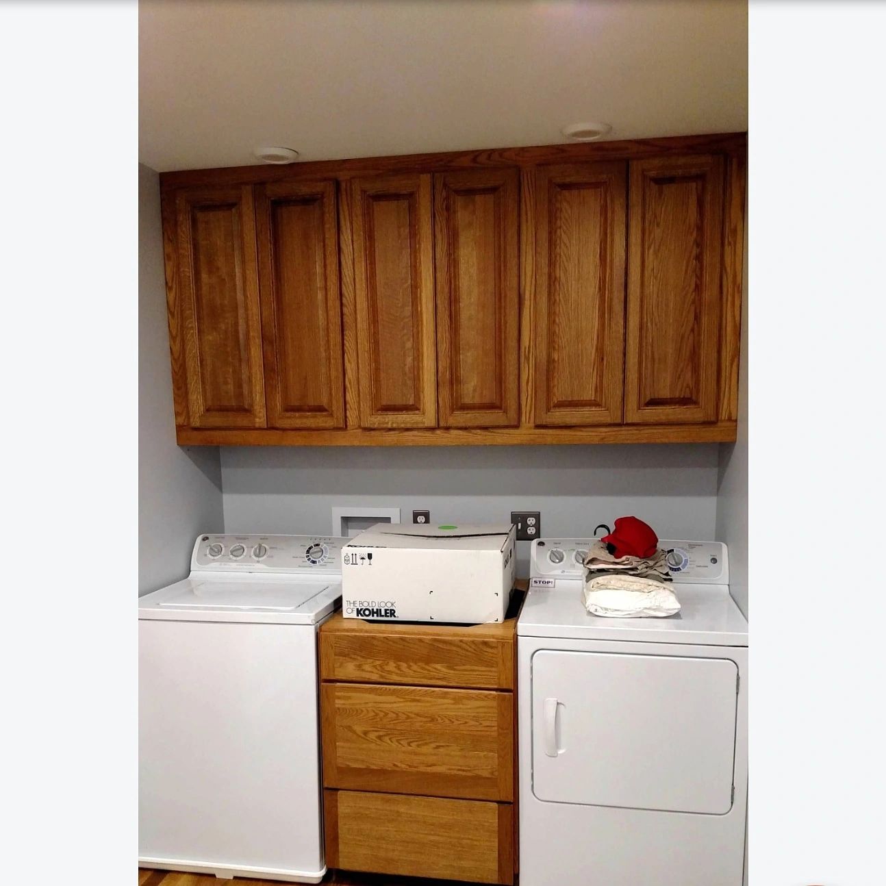 Custom Oak upper and lower cabinets for a combo bathroom and laundry room with drawers and shelves