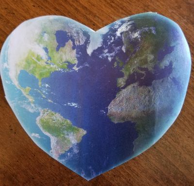 A cutout heart of the planet earth on a wooden background.
