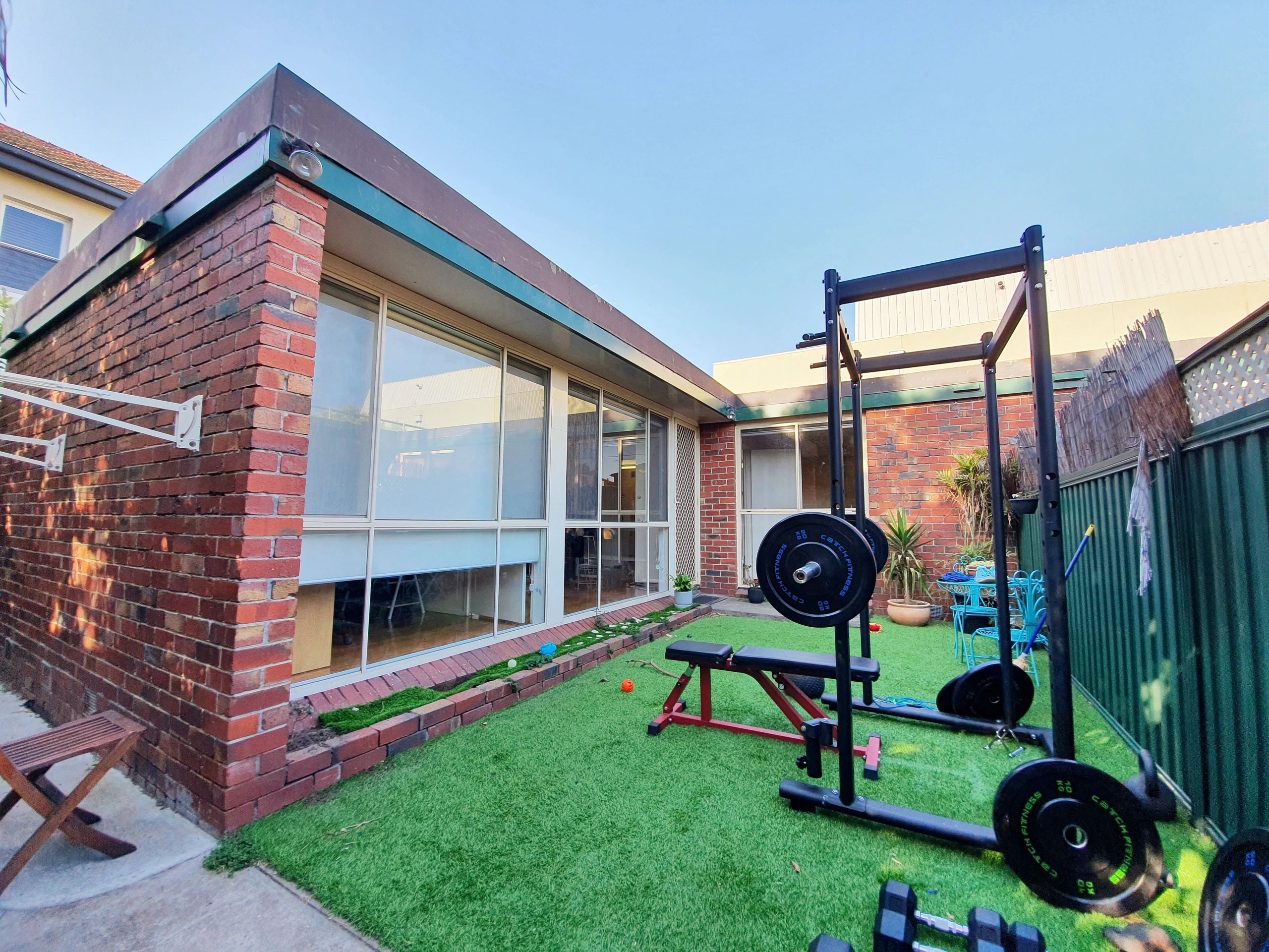 Backyard gym setup with weightlifting equipment and outdoor furniture.