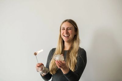 A female, smiling, holding a fire torch and a glass cup