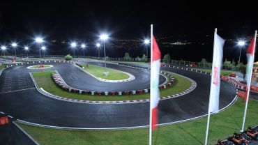 A brightly lit go-kart racing track at night.