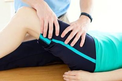 A physical therapist is doing a hands-on assessment of a patient.