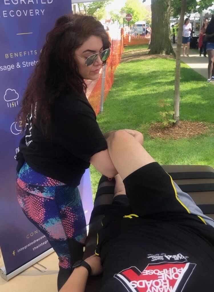 Sports massage therapist providing massage and stretch therapy to runner 