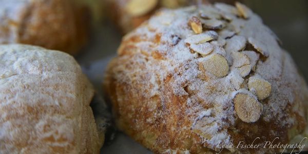 Freshly baked croissants and loaves of sweet bread topped with sliced nuts. 