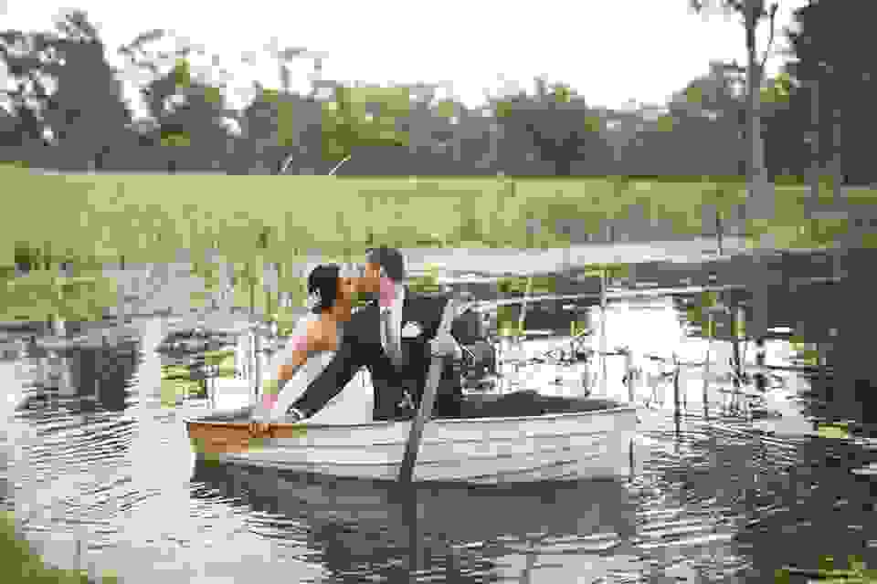 Happily married couple kissing on a row boat.