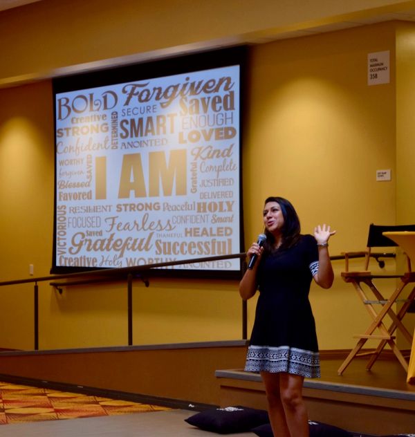 Woman speaking with a motivational word cloud behind her.