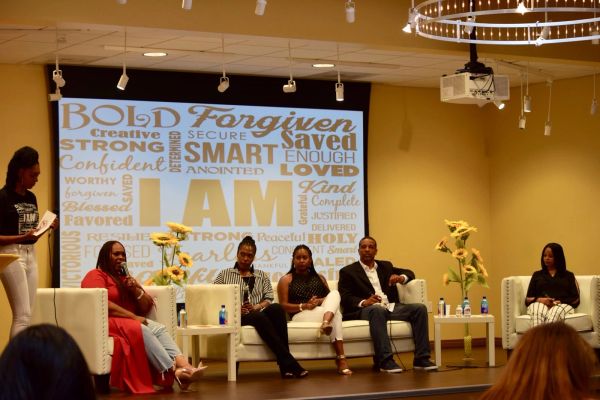 Panel discussion with diverse speakers in front of a positive word cloud.