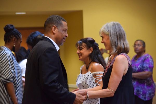 People warmly greeting each other at a social event indoors.