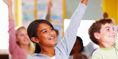 Happy students in classroom with raised hands, knowing the answer to a question.