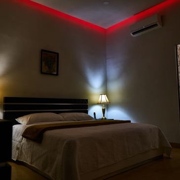 Cozy bedroom with ambient red and yellow lighting and a neatly made bed.