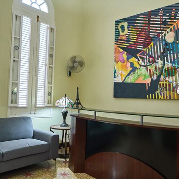 Cozy room with grey sofa, colorful abstract painting, and decorative lamp.