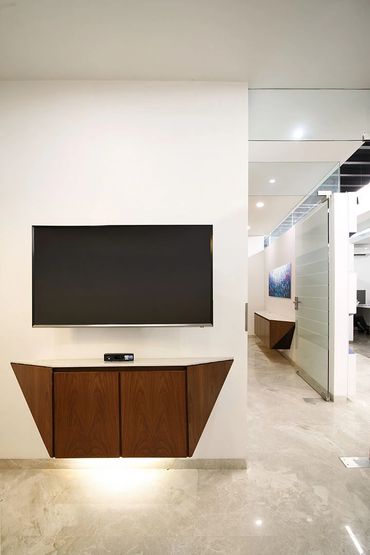 Modern wall-mounted TV with a sleek wooden cabinet and soft floor lighting.