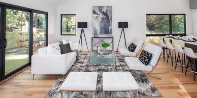 Bright modern living room with white furniture and large windows.