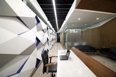 Modern office reception with geometric wall design and sleek furniture.