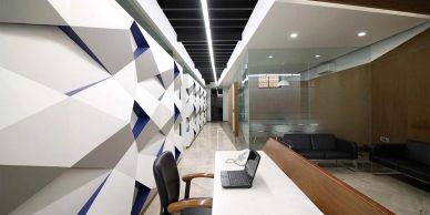 Modern office reception with geometric wall design and sleek furniture.