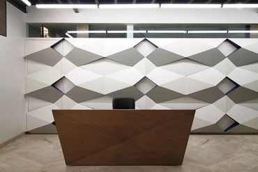 Modern office reception desk with geometric wall design.