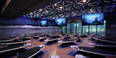 Indoor surf fitness studio with surfboards on platforms and wave-themed decor.