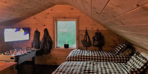 Cozy wooden attic room with two beds and a foosball table.