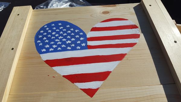 Heart painted with the American flag design on wood.