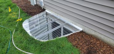 Clear sloped window well cover designed for basement protection and water drainage.