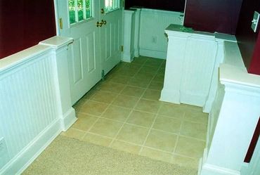 Basement Remodel with beadboard wainscoting, custom columns and trim work with tile floor entry way