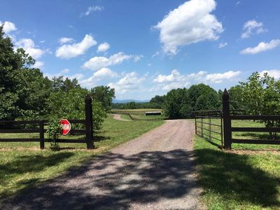 The front gate is opened to Still Pond farm. You can see green grass and mountains in the distance.