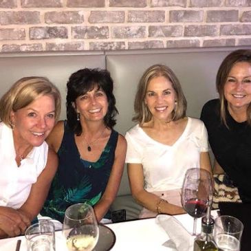 Four women smiling at a dining table.