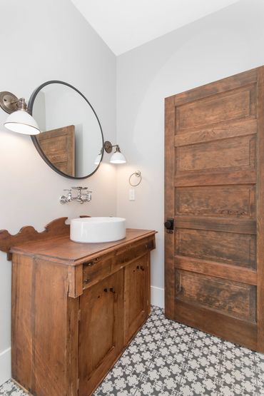 Rustic wooden bathroom vanity and door with patterned floor tiles.