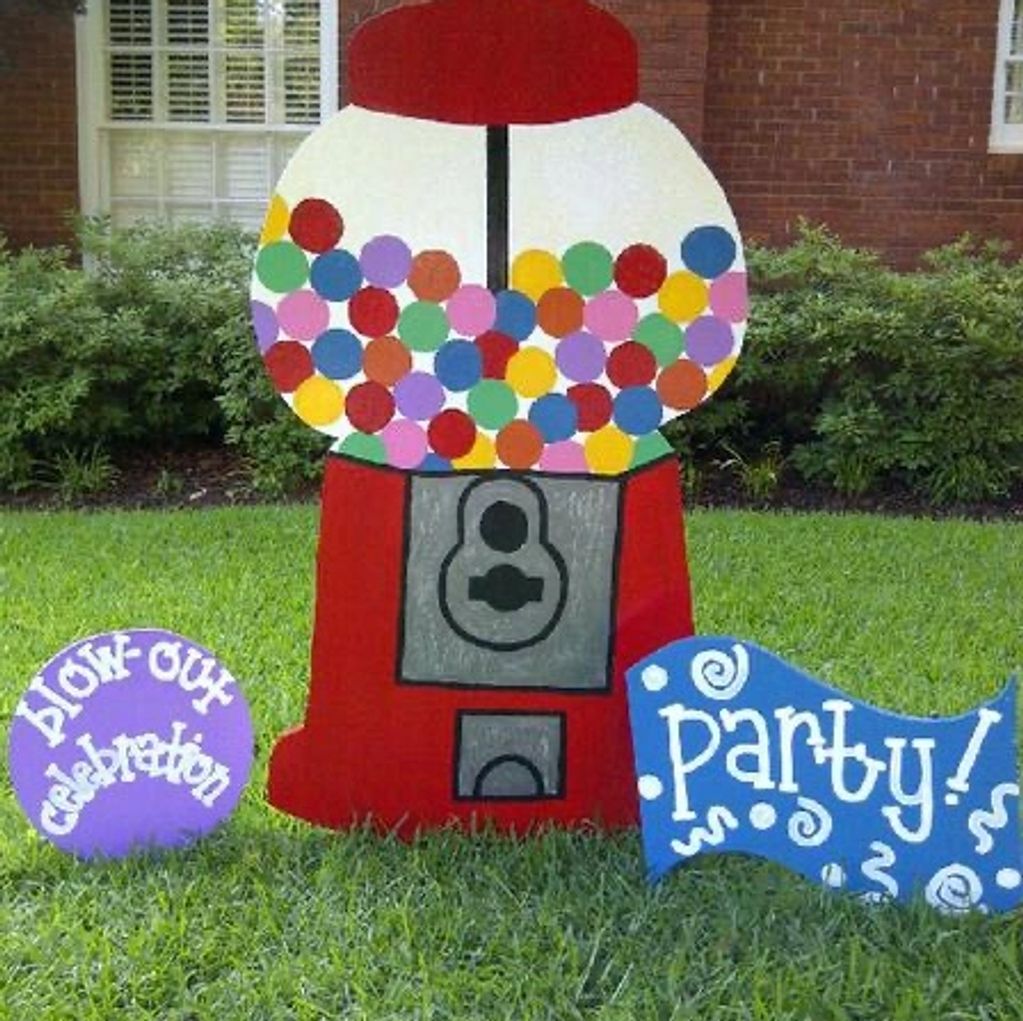 Colorful gumball machine yard decoration with celebration and party signs.