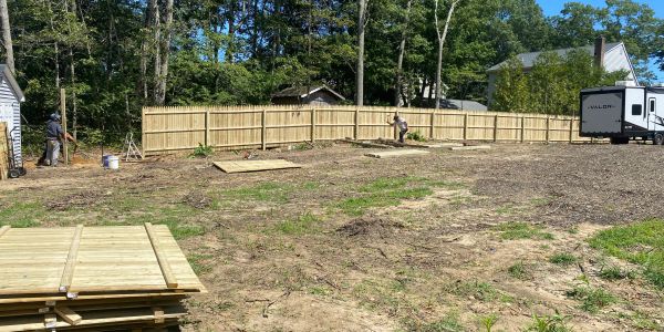 New wooden fence being installed in a backyard.