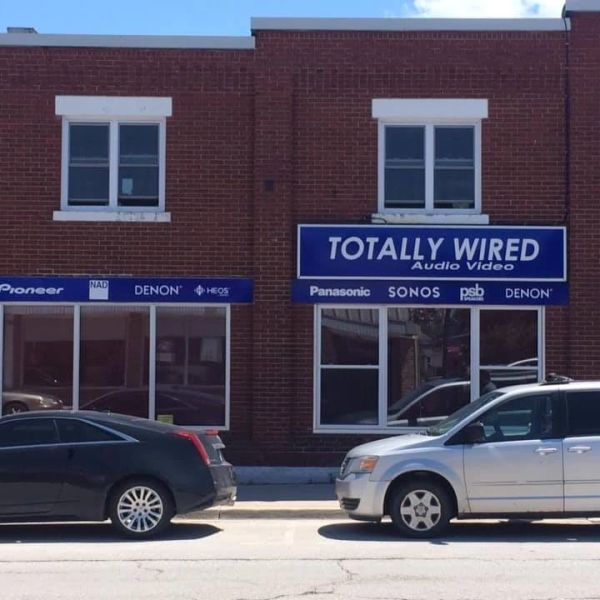 Brick building with audio video store signage and parked cars.