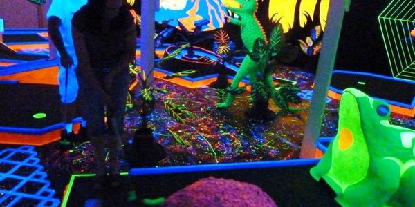 Black light indoor mini golf course lit up.