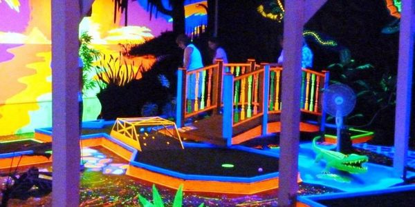 Black light indoor mini golf course lit up.