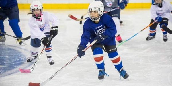 Young kids playing ice hockey in a game.