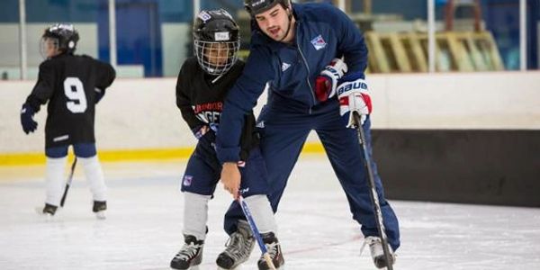 Hockey coach teaching a young player on the ice rink.