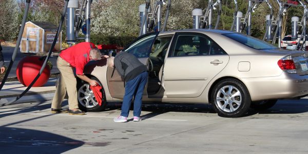 Waves Express Car Wash team member assisting customer in the parking lot vacuum area.