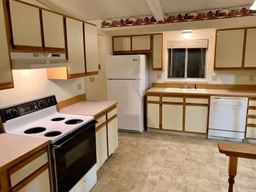 A clean kitchen with white appliances and wood-trimmed cabinets.