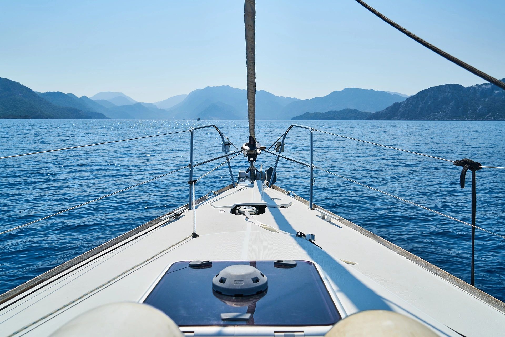 View from a sailboat looking out at the sea and distant mountains.