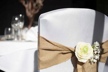 Close up of hessian chair sash with artificial flowers as decor.